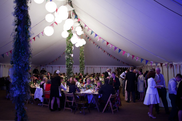 Interior paper lantern lighting with bunting in a traditional canvas marquee.